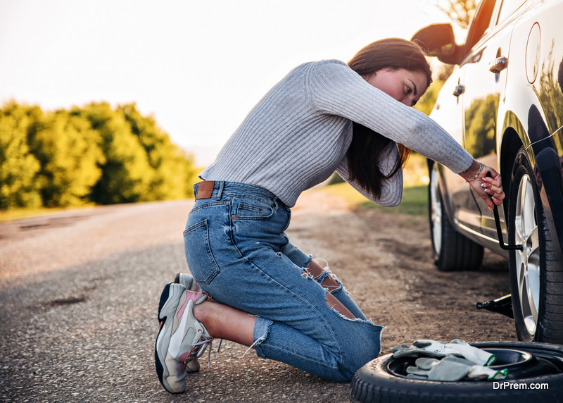 Woman changing wheel after a car breakdown