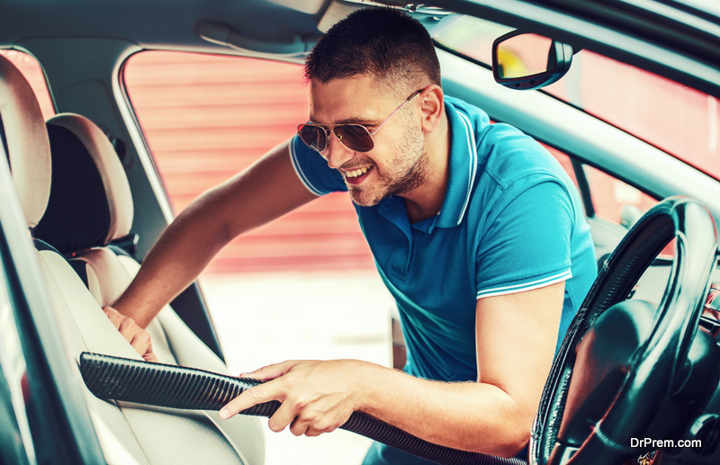 Man cleaning the interior of his car with vacuum cleaner. Car care concept