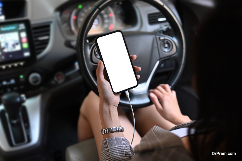 Cropped shot of young woman using smart phone while sitting in car.