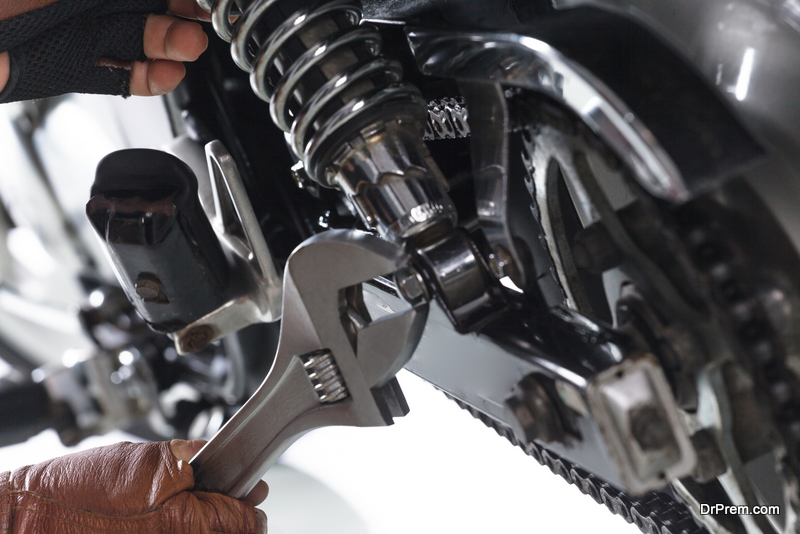 Cropped view of Mechanic using a wrench on a motorcycle on white background
