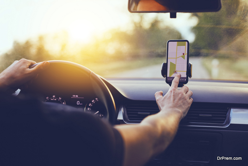 Driver using GPS navigation in mobile phone while driving car at sunset